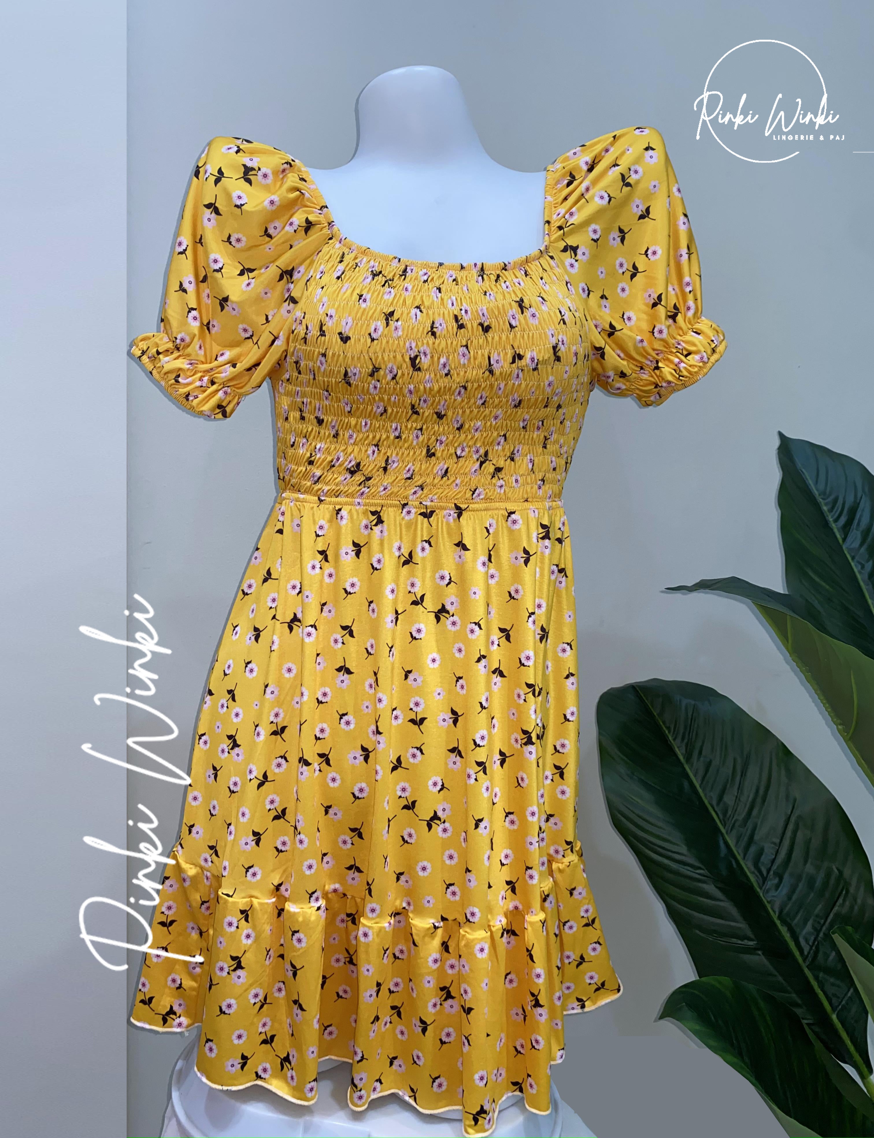 Yellow floral dress on a mannequin with a plant in the background